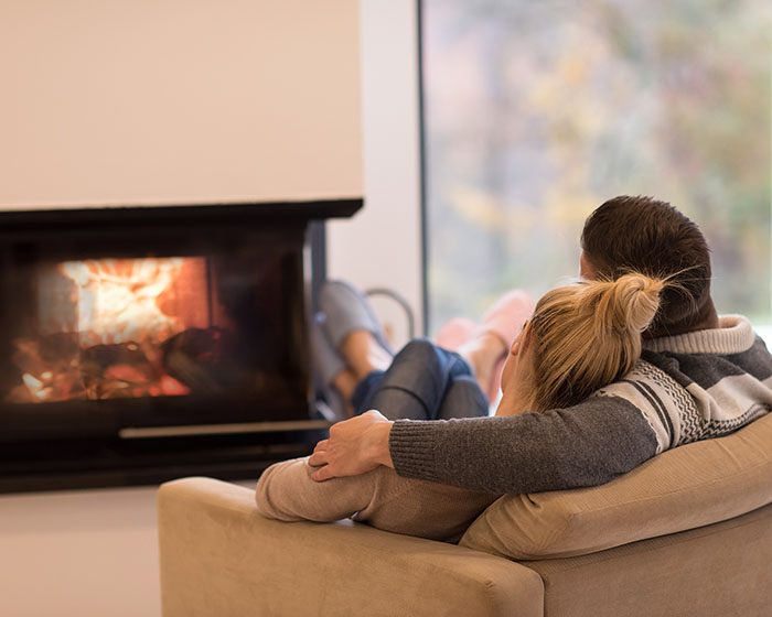 couple sitting on sofa in front of fireplace a